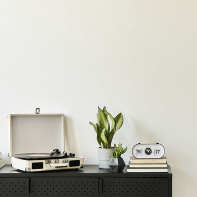 black console table with record player, plants, books and clock with wall painted in the Almond Milk color