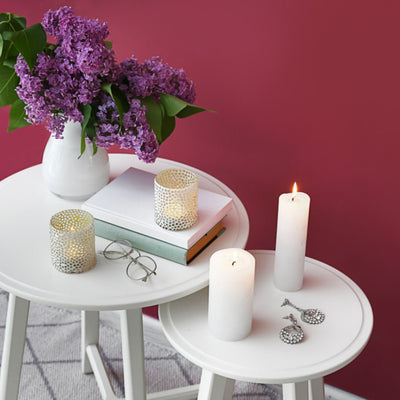 Small accent area with white side tables decorated with white candes, books, and a white vase filled with purple flowers. Accent Wall painted in Cherry Berry