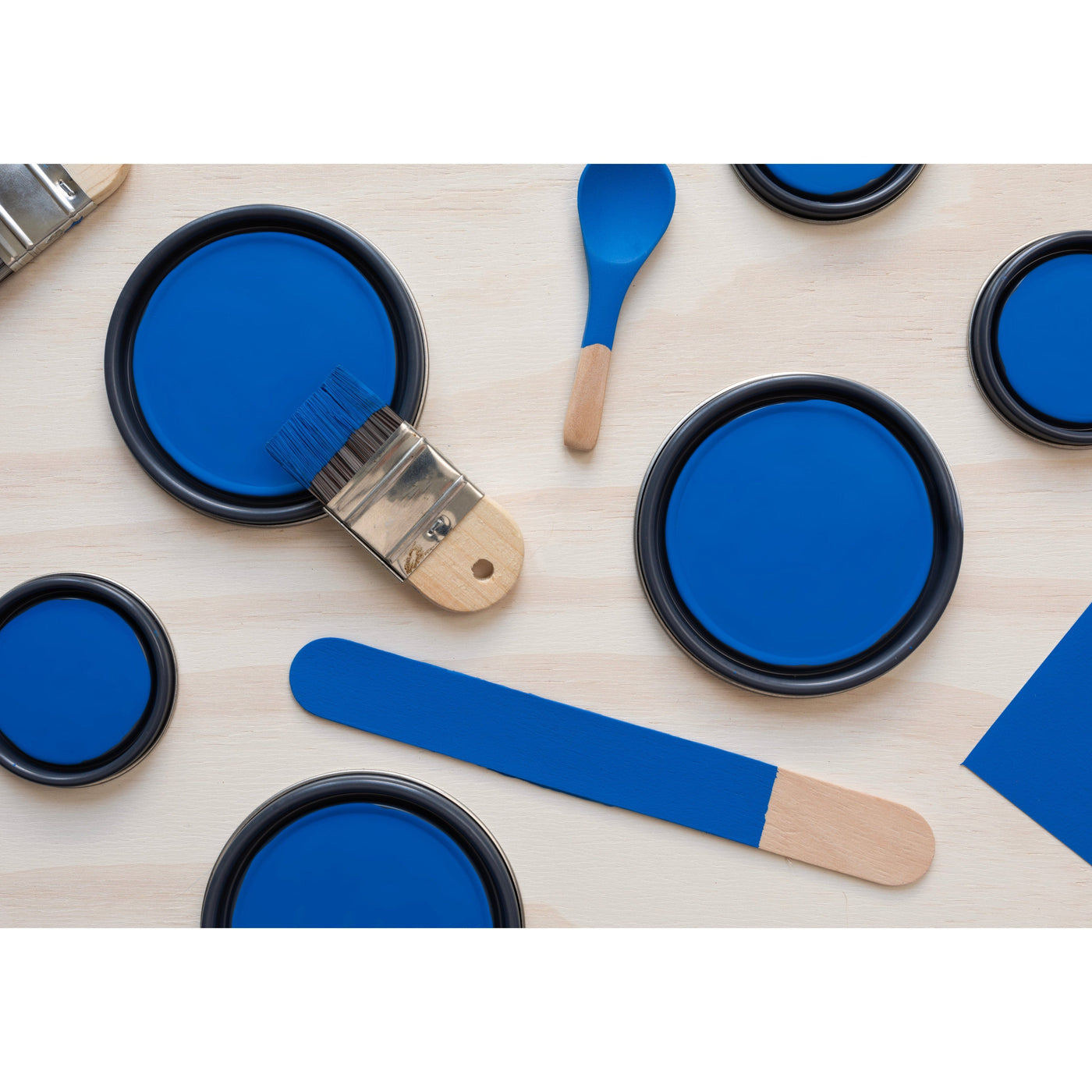 flatlay with paint lids, small paint brush, wooded spoons and rounded sticks painted in Beautiful Blue