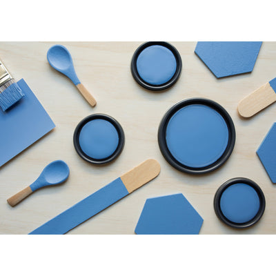 flatlay with wood hexagons, small paint brush, paint lids and wooden spoons all painted in Cornflower