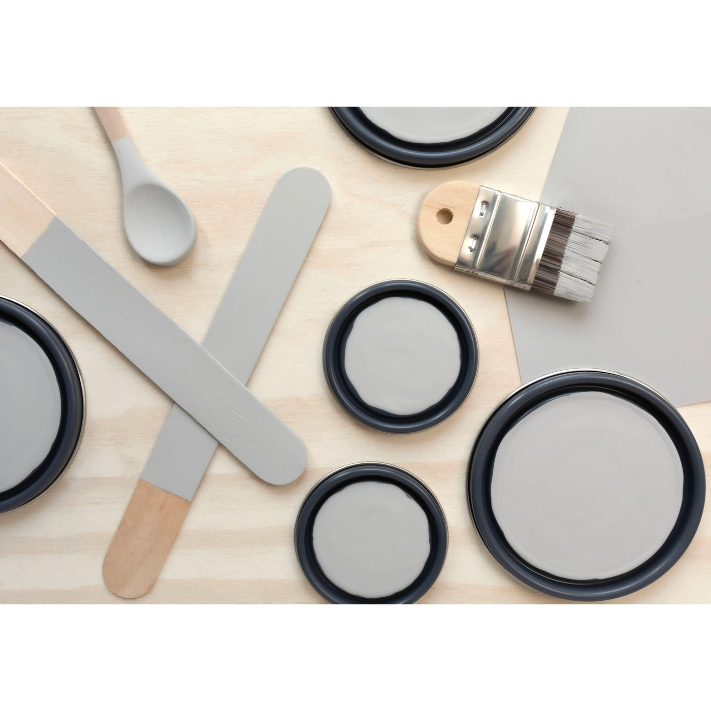  flatlay with paint lids, small paint brush, wooden spoons and rounded sticks painted in Gray Pearl