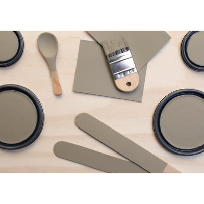 flatlay with paint lids, small paint brush, wooded spoons and rounded sticks painted in Calico Rock