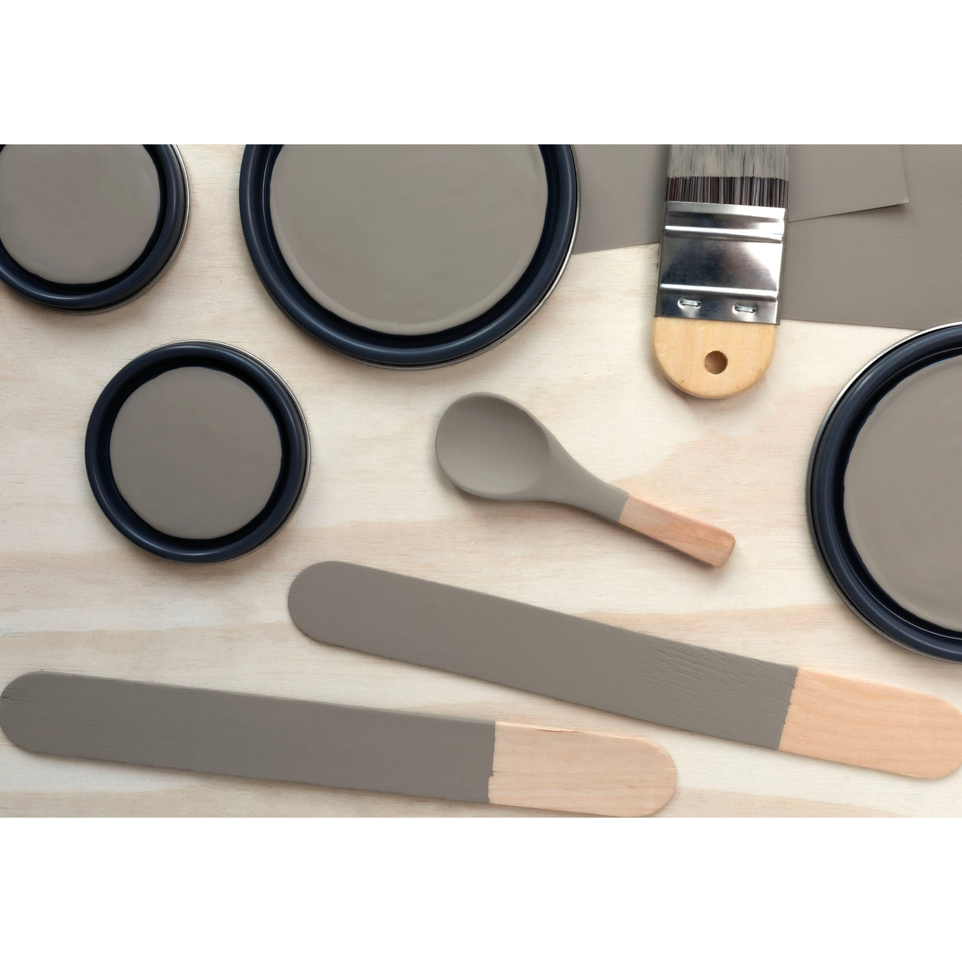 flatlay with paint lids, small paint brush, wooded spoons and rounded sticks painted in Barnwood Gray