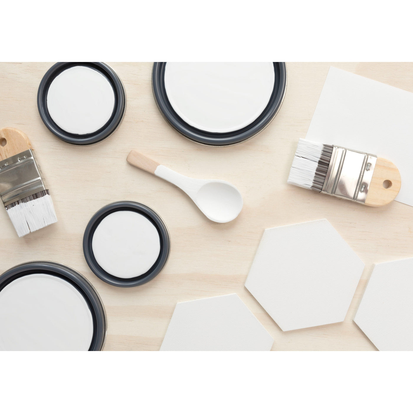 flatlay with wood hexagons, small paint brush, paint lids and wooden spoons all painted in Classic White