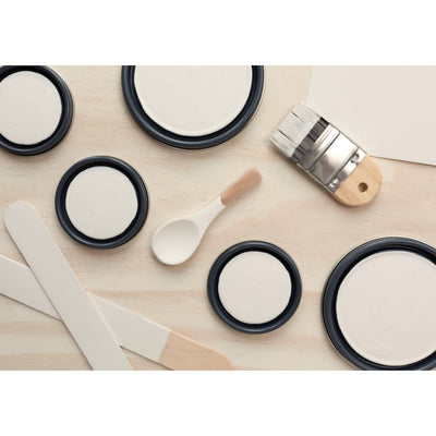 flatlay with paint lids, small paint brush, wooden spoons and rounded sticks painted in Historic White