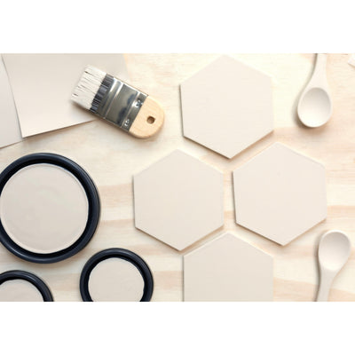 flatlay with wood hexagons, small paint brush, paint lids and wooden spoons all painted in Bone