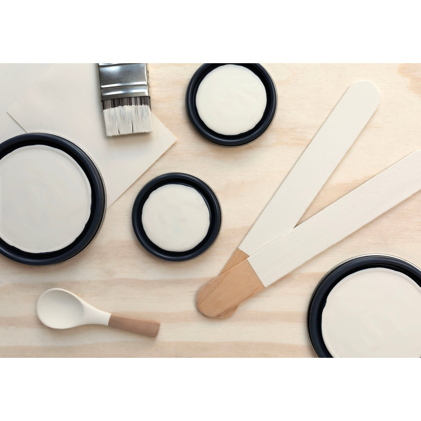 flatlay with paint lids, small paint brush, wooded spoons and rounded sticks painted in Ball of String