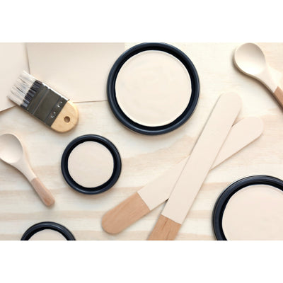 flatlay with paint lids, small paint brush, wooded spoons and rounded sticks painted in Almond