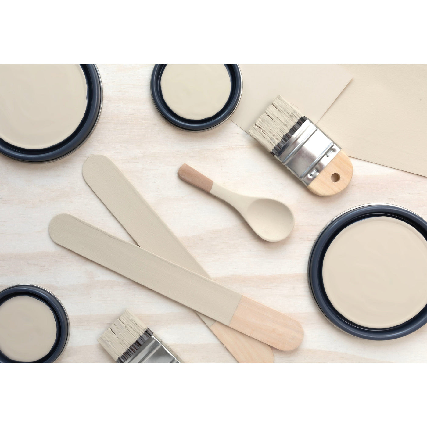  flatlay with paint lids, small paint brush, wooded spoons and rounded sticks painted in Cochise