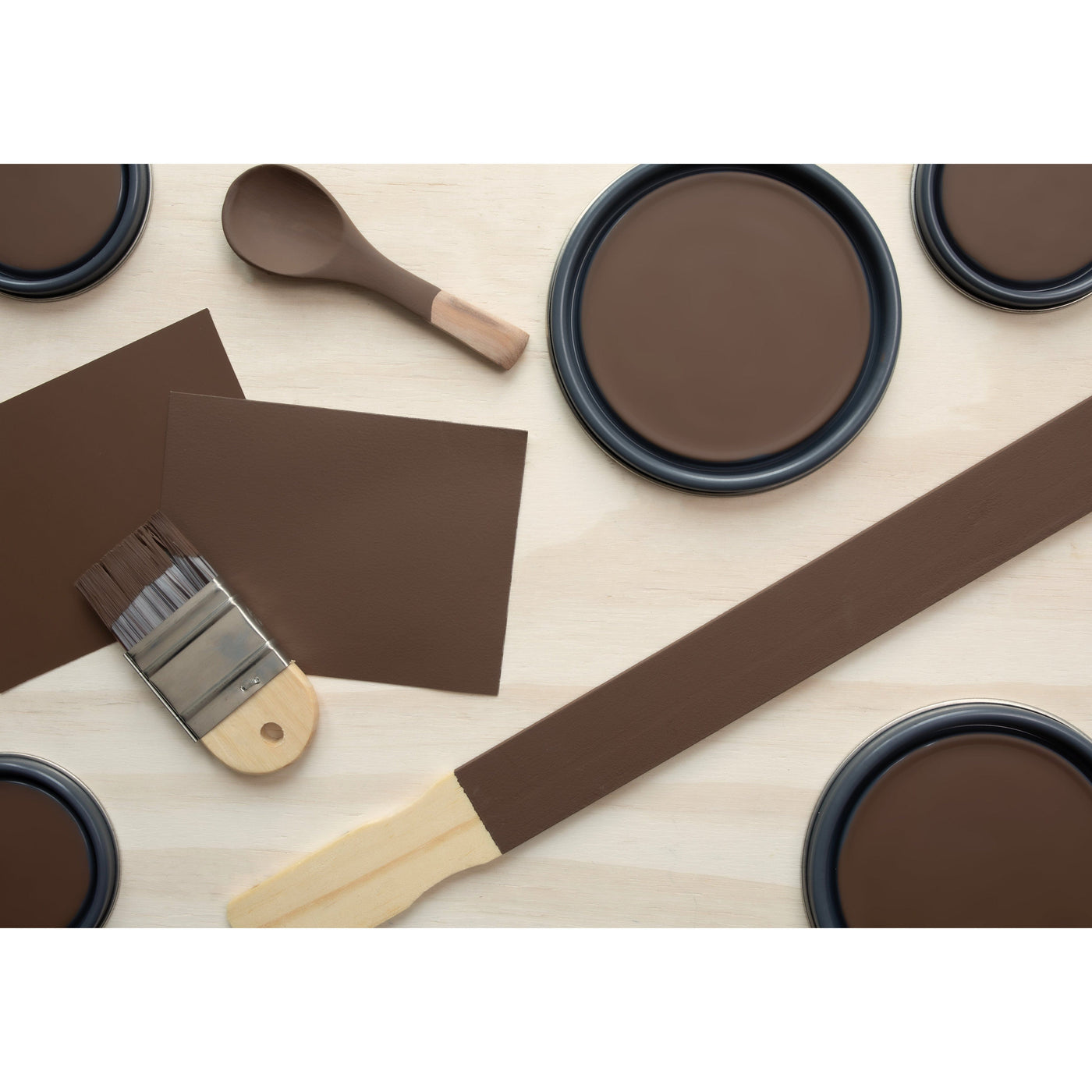 flatlay with paint lids, small paint brush, wooden spoons and paint stick painted in Deep Brown