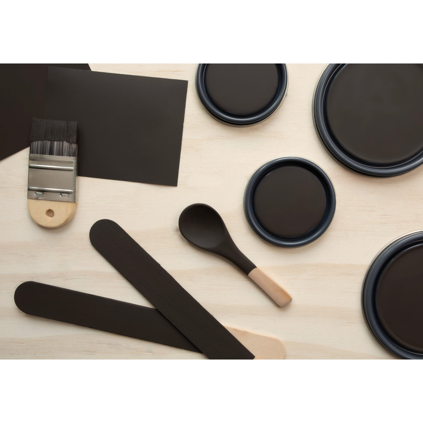 flatlay with paint lids, small paint brush, wooden spoons and rounded sticks painted in Espresso Macchiato