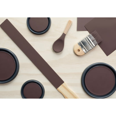 flatlay with paint lids, small paint brush, wooded spoons and rounded sticks painted in Bourbon Truffle