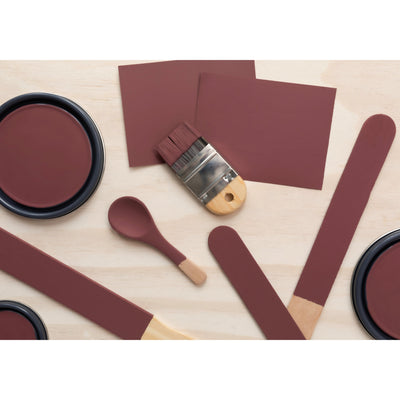 flatlay with paint lids, small paint brush, wooded spoons and rounded sticks painted in Antique Garnet