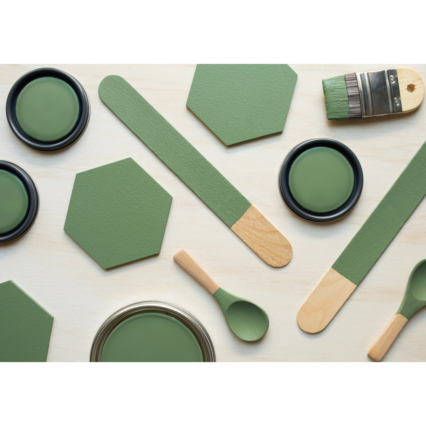 flatlay with wood hexagons, small paint brush, paint lids and wooden spoons all painted in Forest Path