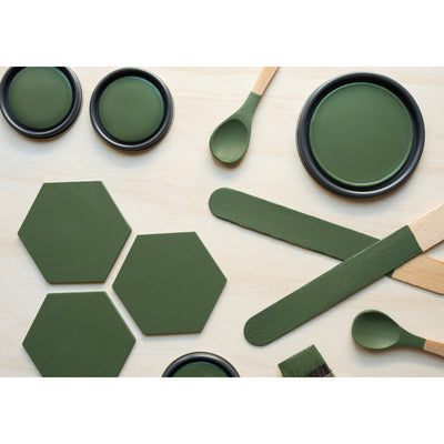flatlay with wood hexagons, small paint brush, paint lids and wooden spoons all painted in Green Bayou