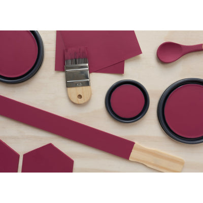 flatlay with wood hexagons, small paint brush, paint lids and wooden spoons all painted in Cherry Berry