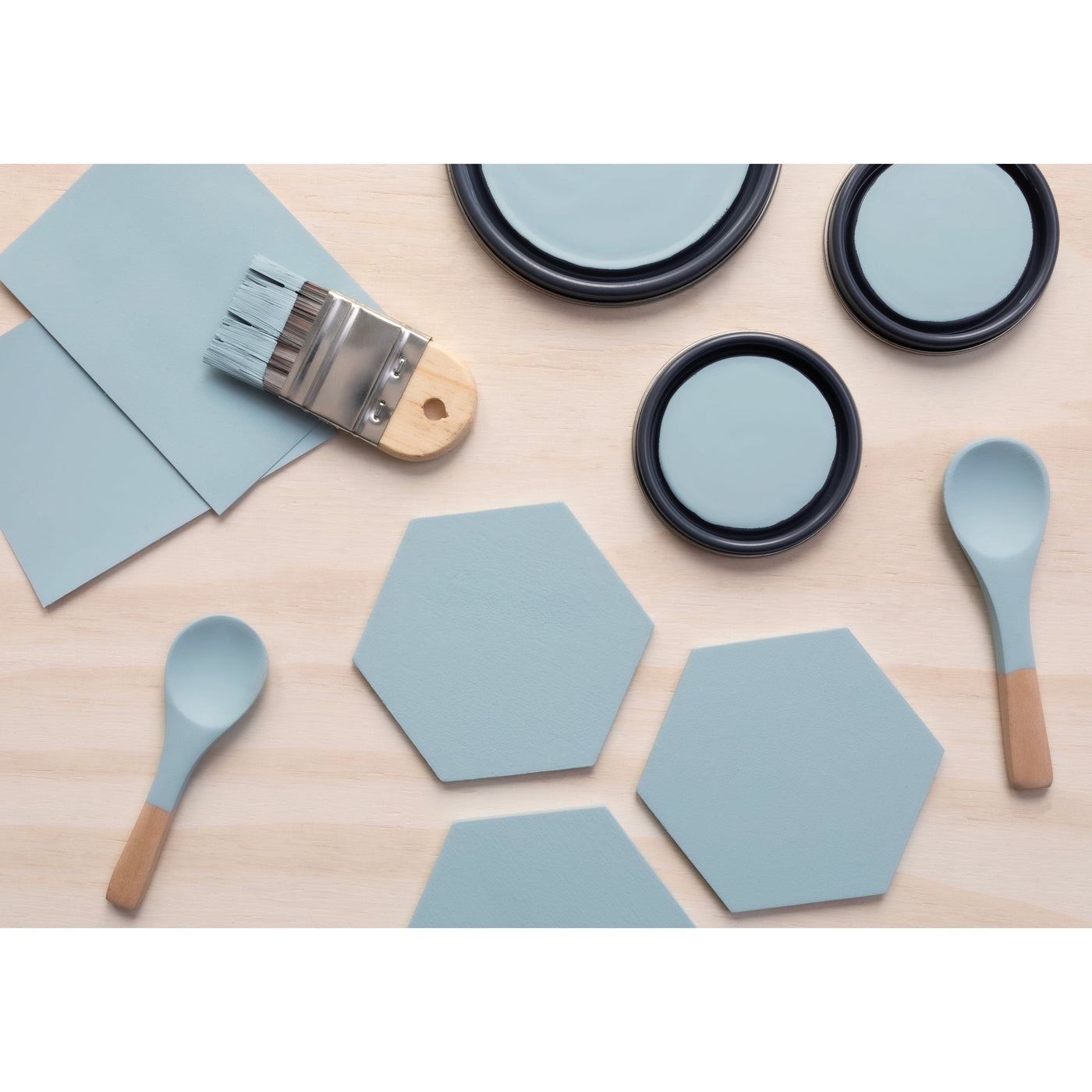 flatlay with wood hexagons, small paint brush, paint lids and wooden spoons all painted in Blue Spruce