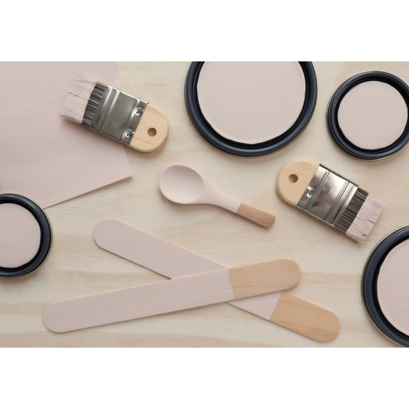 flatlay with paint lids, small paint brush, wooded spoons and rounded sticks painted in Blushing Bride
