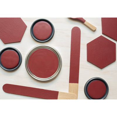 flatlay with wood hexagons, small paint brush, paint lids and wooden spoons all painted in Barn Red