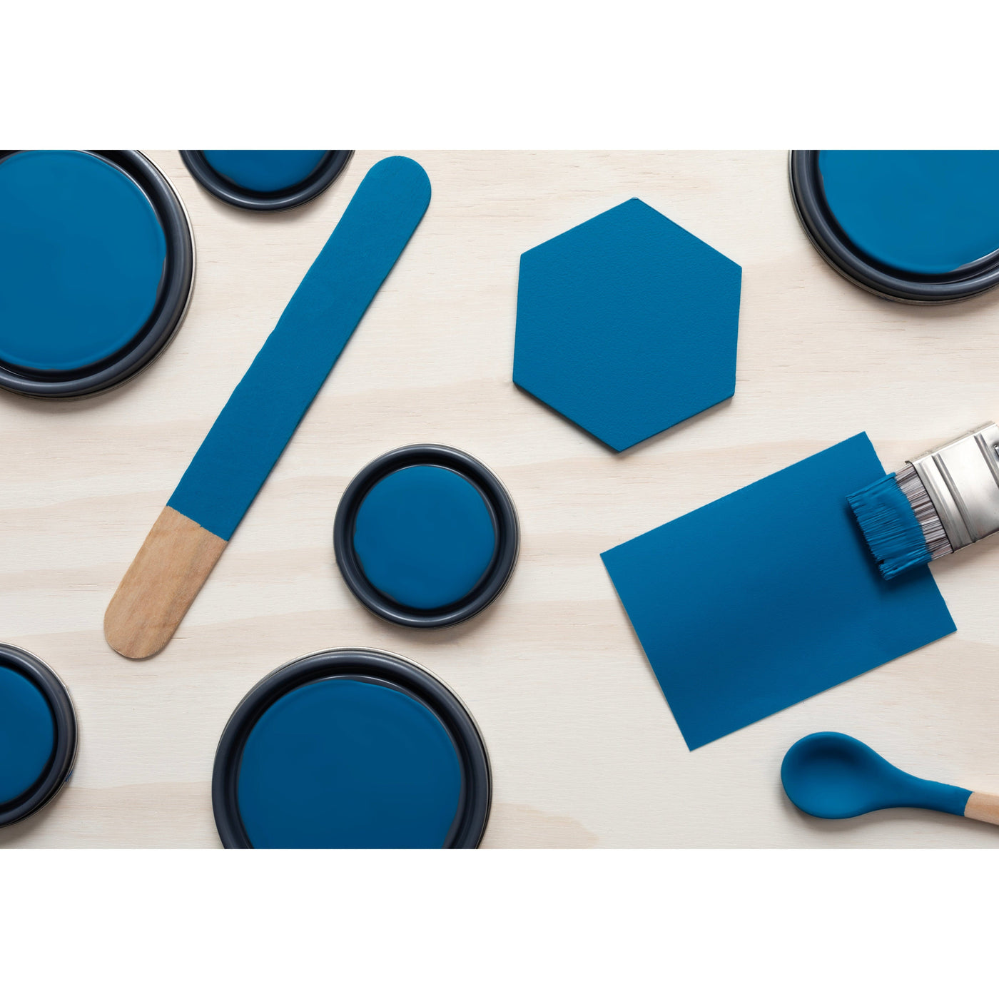 flatlay with wood hexagons, small paint brush, paint lids and wooden spoons all painted in Blue Velvet